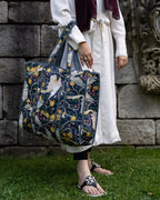 Person holding a floral-patterned bag against a stone wall background