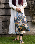 Person holding a patterned bag against a stone wall background