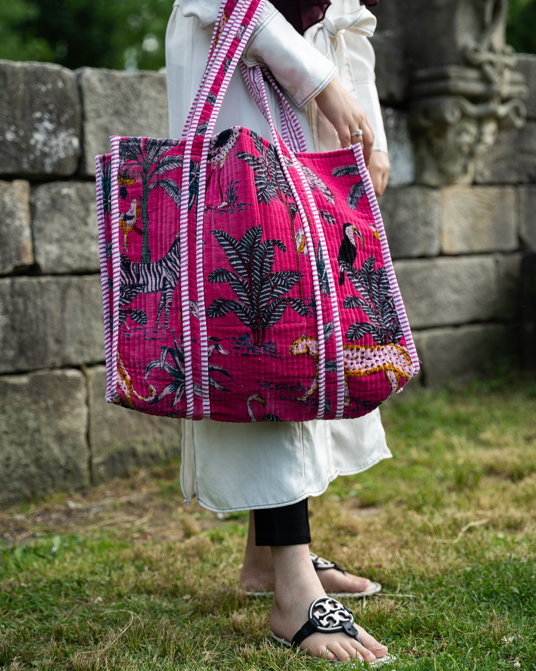 Person holding a pink and black patterned bag outdoors.