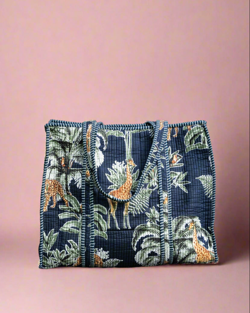 Navy blue handbag with floral and animal pattern on a stone surface with greenery in the background