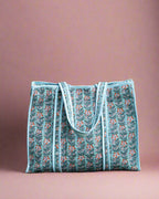 Blue patterned tote bag on a stone surface with greenery in the background