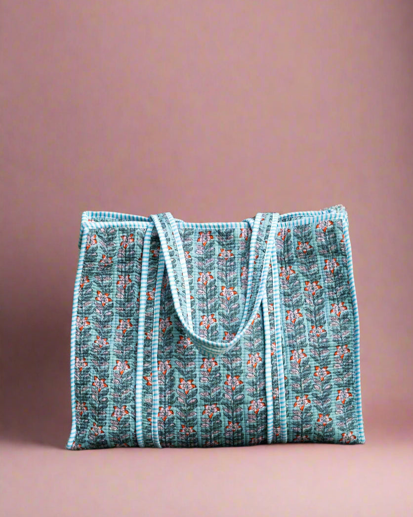 Blue patterned tote bag on a stone surface with greenery in the background