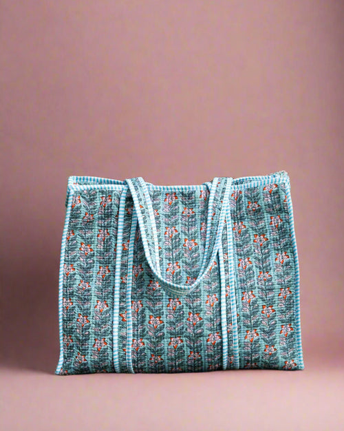 Blue patterned tote bag on a stone surface with greenery in the background