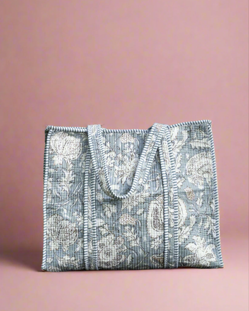 Silver beaded handbag on a stone surface with greenery in the background
