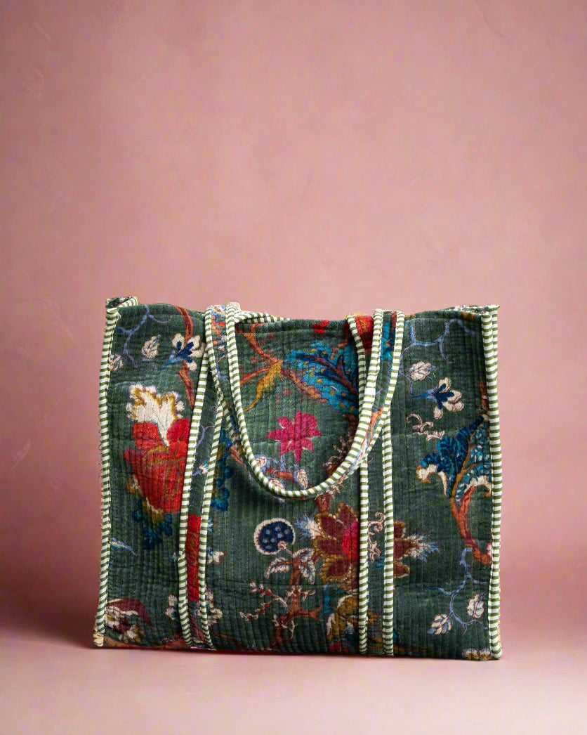 Embroidered handbag with floral patterns on a stone surface with greenery in the background