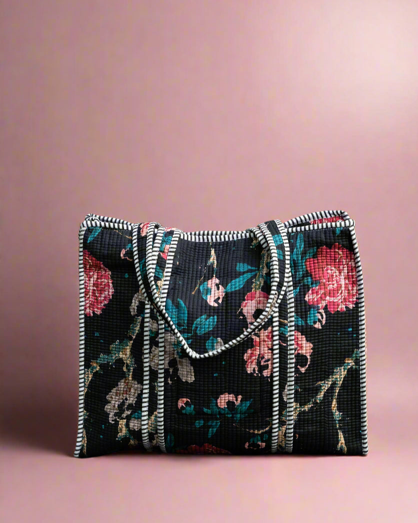 Floral patterned handbag on a stone surface with greenery in the background