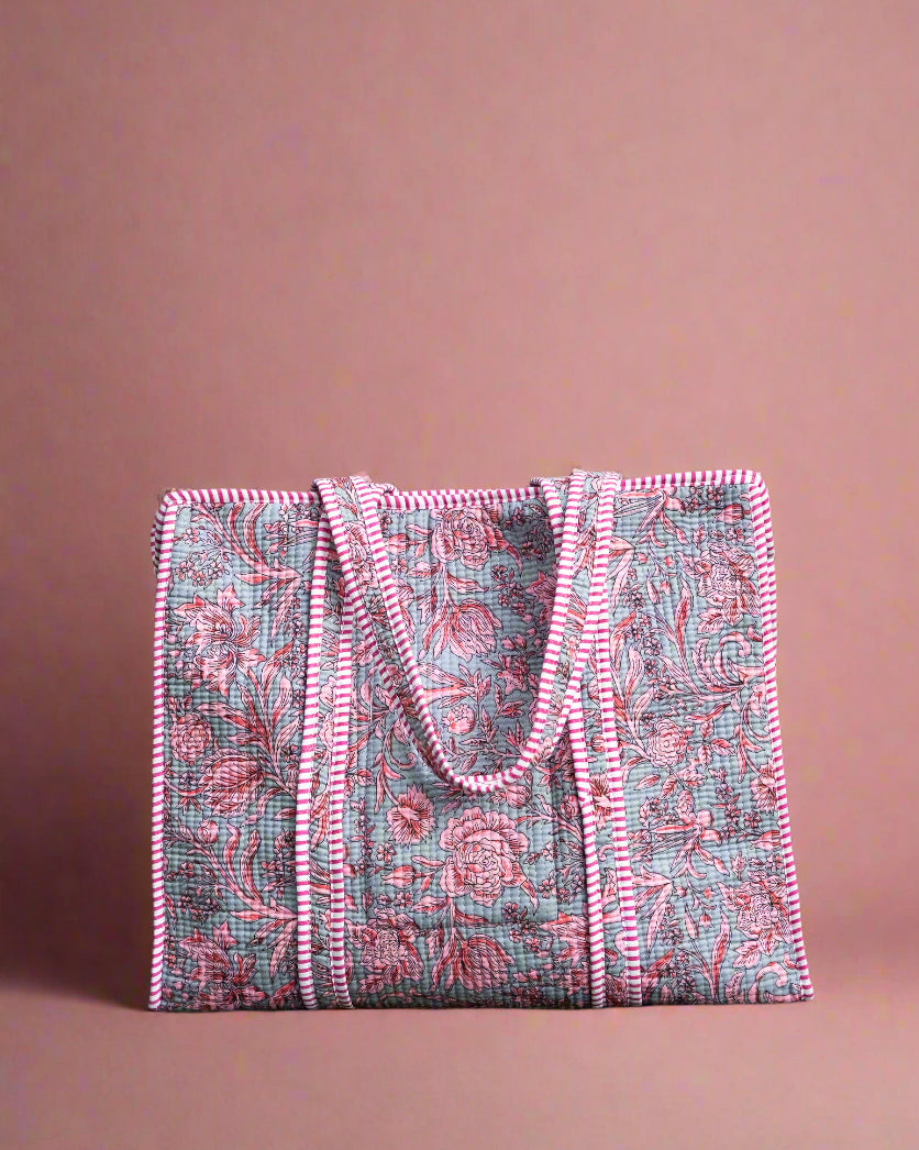 Pink and gray patterned tote bag on a stone surface with greenery in the background