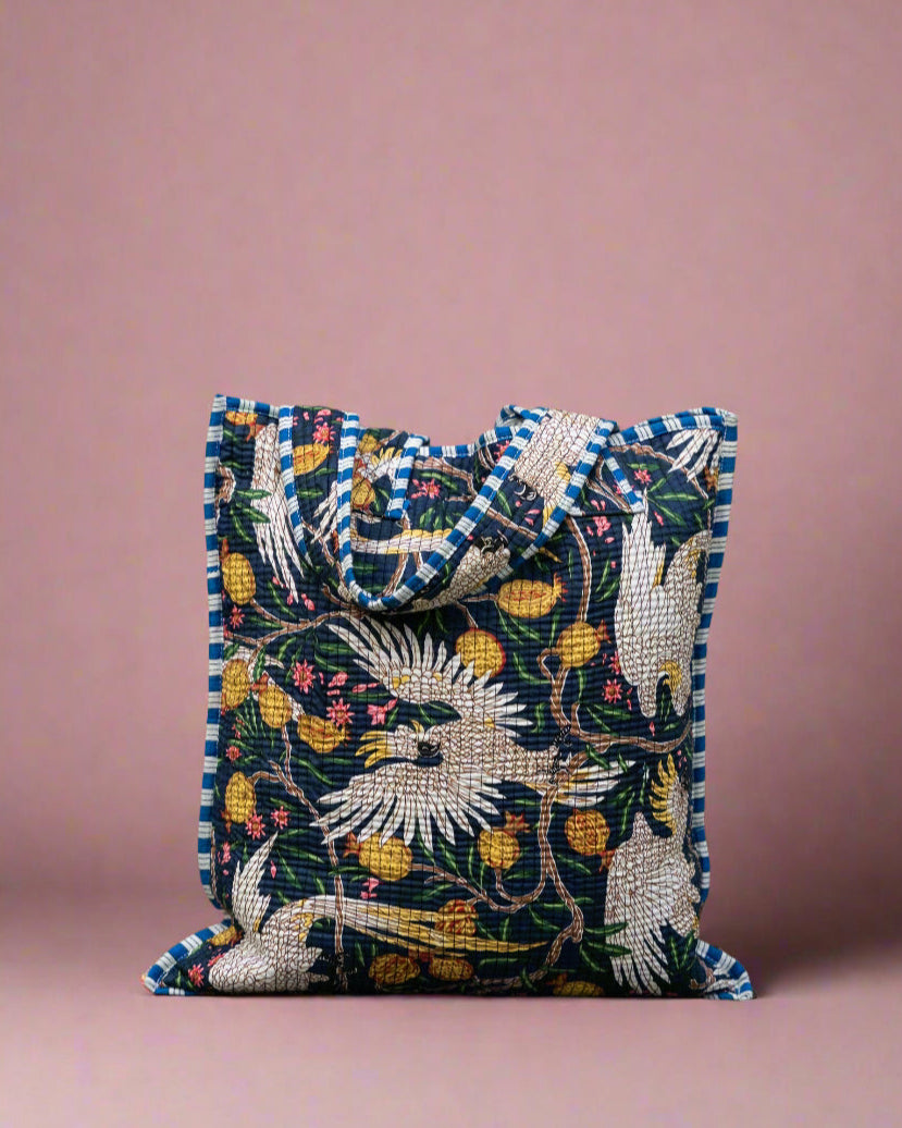 Decorative pillow with floral and bird pattern against a stone wall.