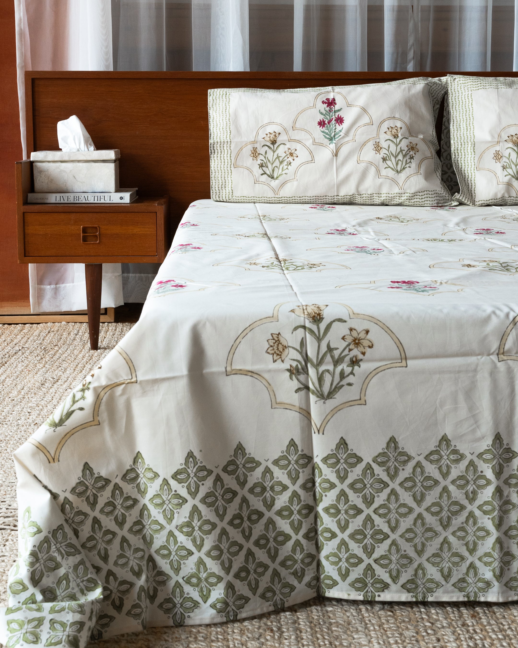Bed with floral and geometric patterned bedding in a bedroom setting.