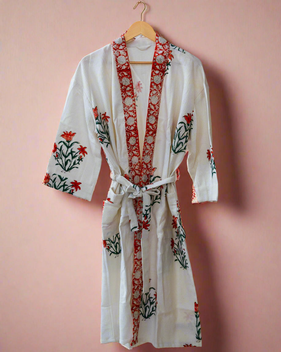 White robe with red and green floral patterns hanging on a wooden rack.