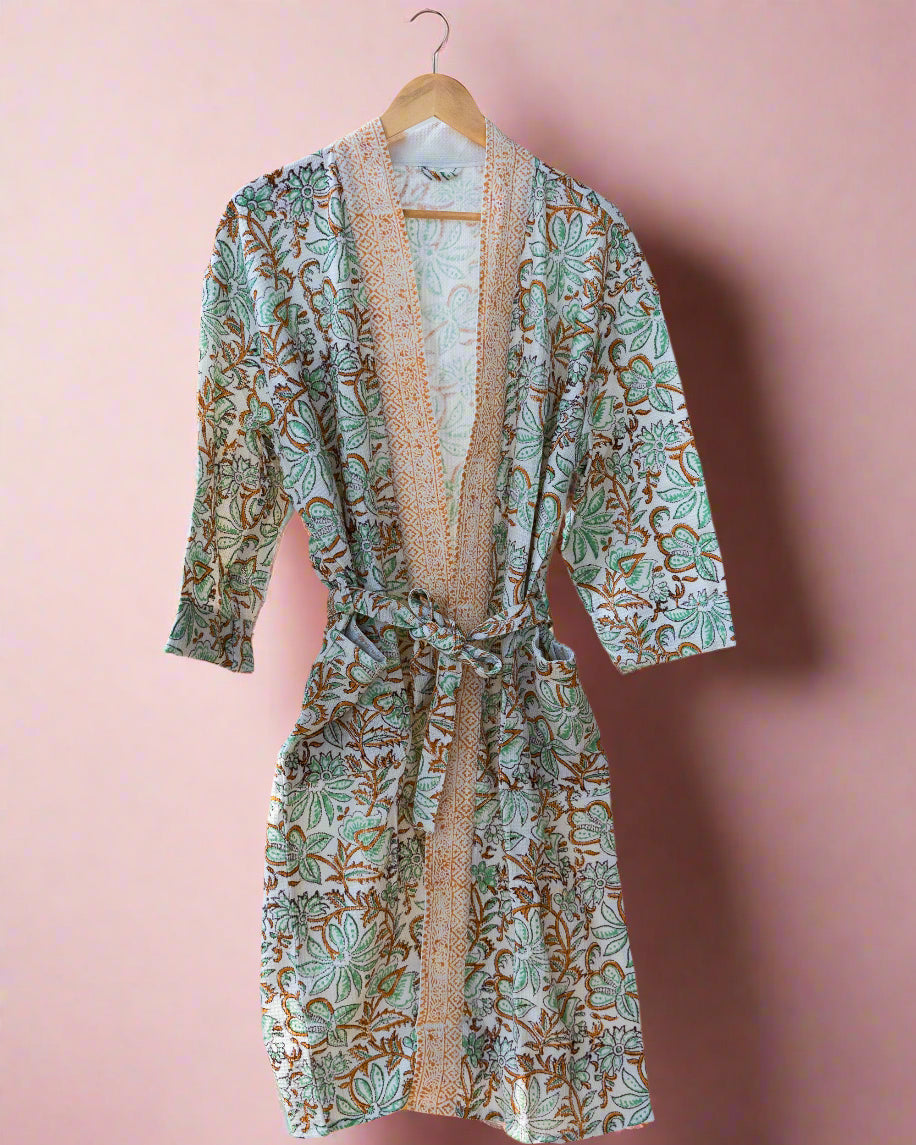 Floral patterned robe hanging on a wooden rack in a room with wooden flooring.