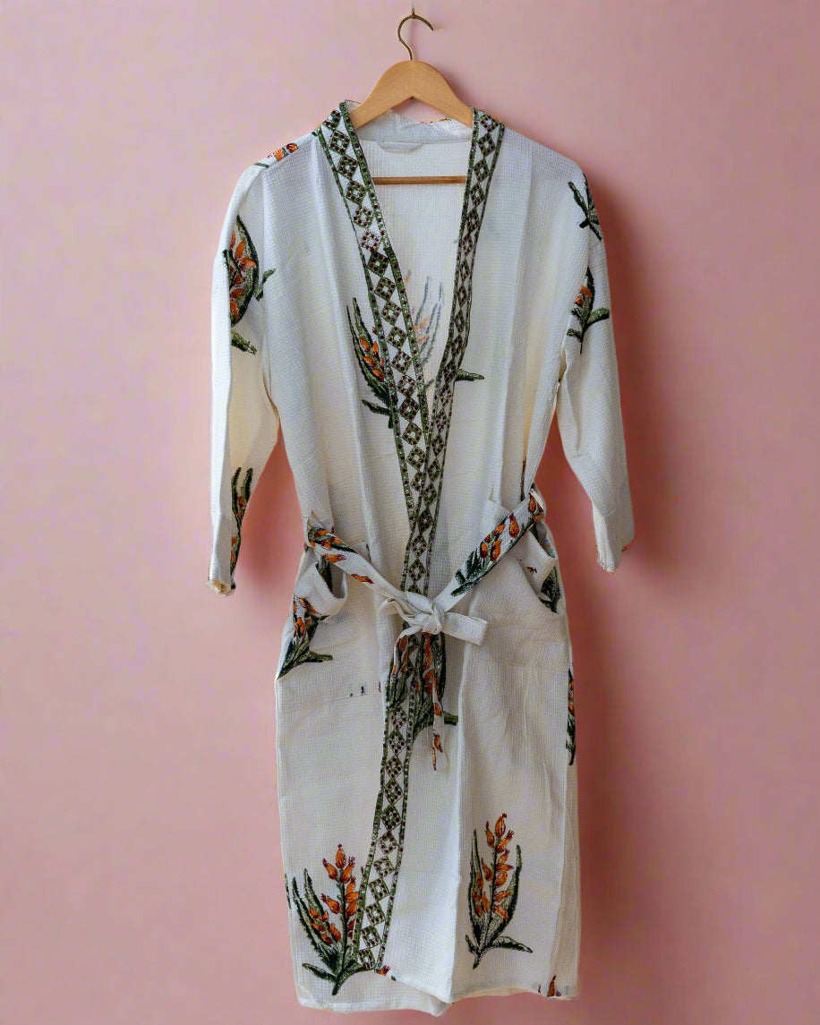 White robe with floral embroidery on a wooden hanger against a neutral background