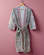 Floral patterned robe hanging on a wooden rack in a room with wooden flooring.